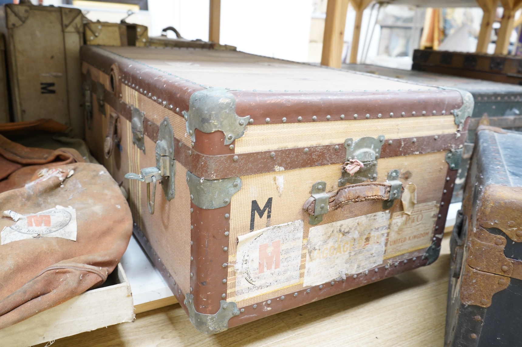 A collection of vintage luggage comprising four early 20th century bound travelling trunks and three kit bags